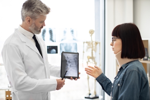 A car accident doctor reviewing a neck injury of a woman in a neck brace.