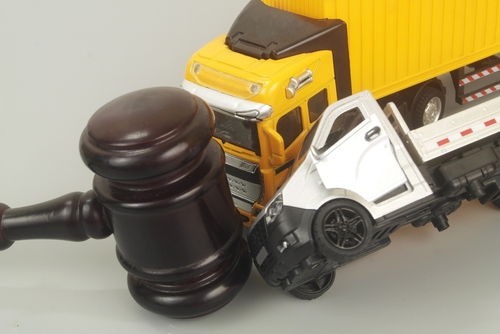 Two toy cars and a gavel representing a legal case being handled by a truck accident lawyer to help a victim.