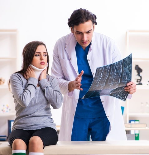 Whiplash doctor going over x-rays of a patient's neck while she in a neck brace to help her get whiplash treatment.